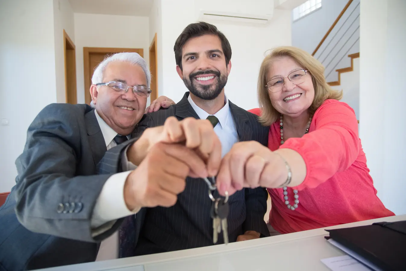 Elderly couple receiving house keys from a realtor while discussing a 50 year mortgage loan