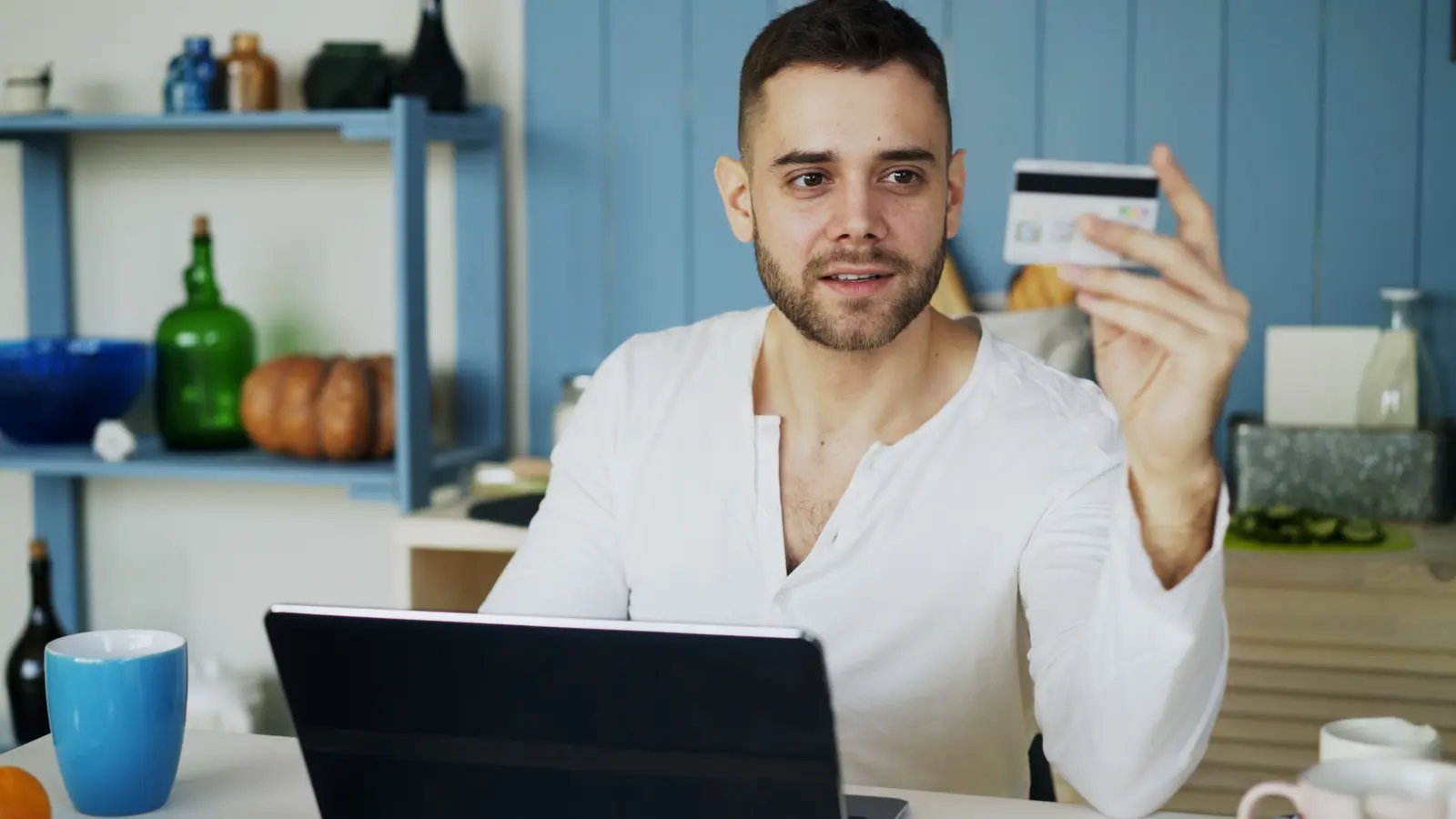 Man at a desk using a laptop and holding a credit card for HDFC application