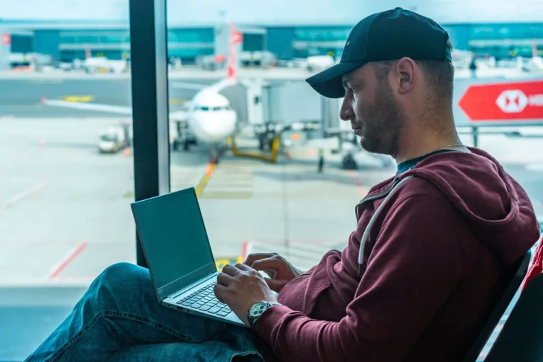 Business traveler working on a laptop in an airport terminal with a plane outside