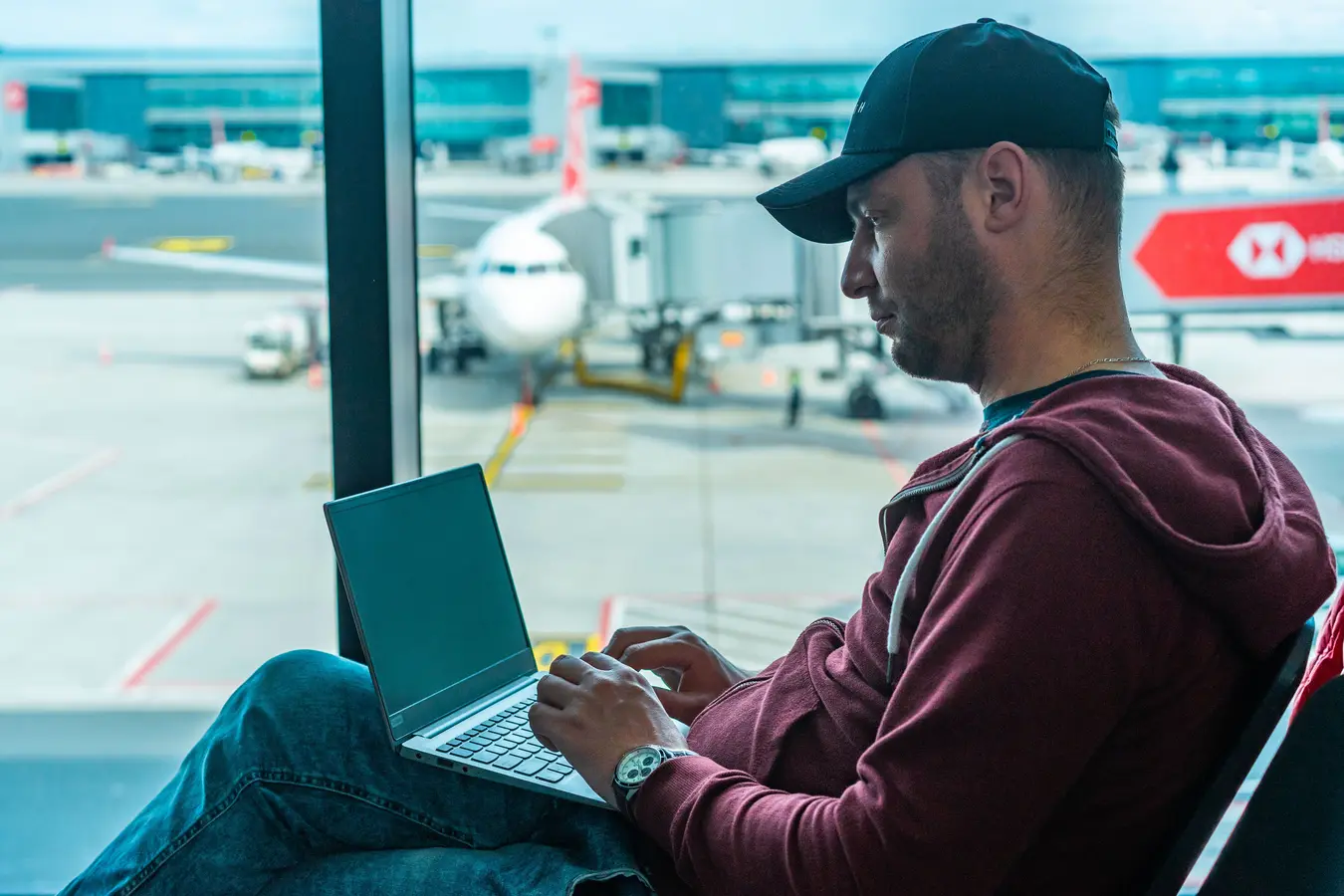 Business traveler working on a laptop in an airport terminal with a plane outside