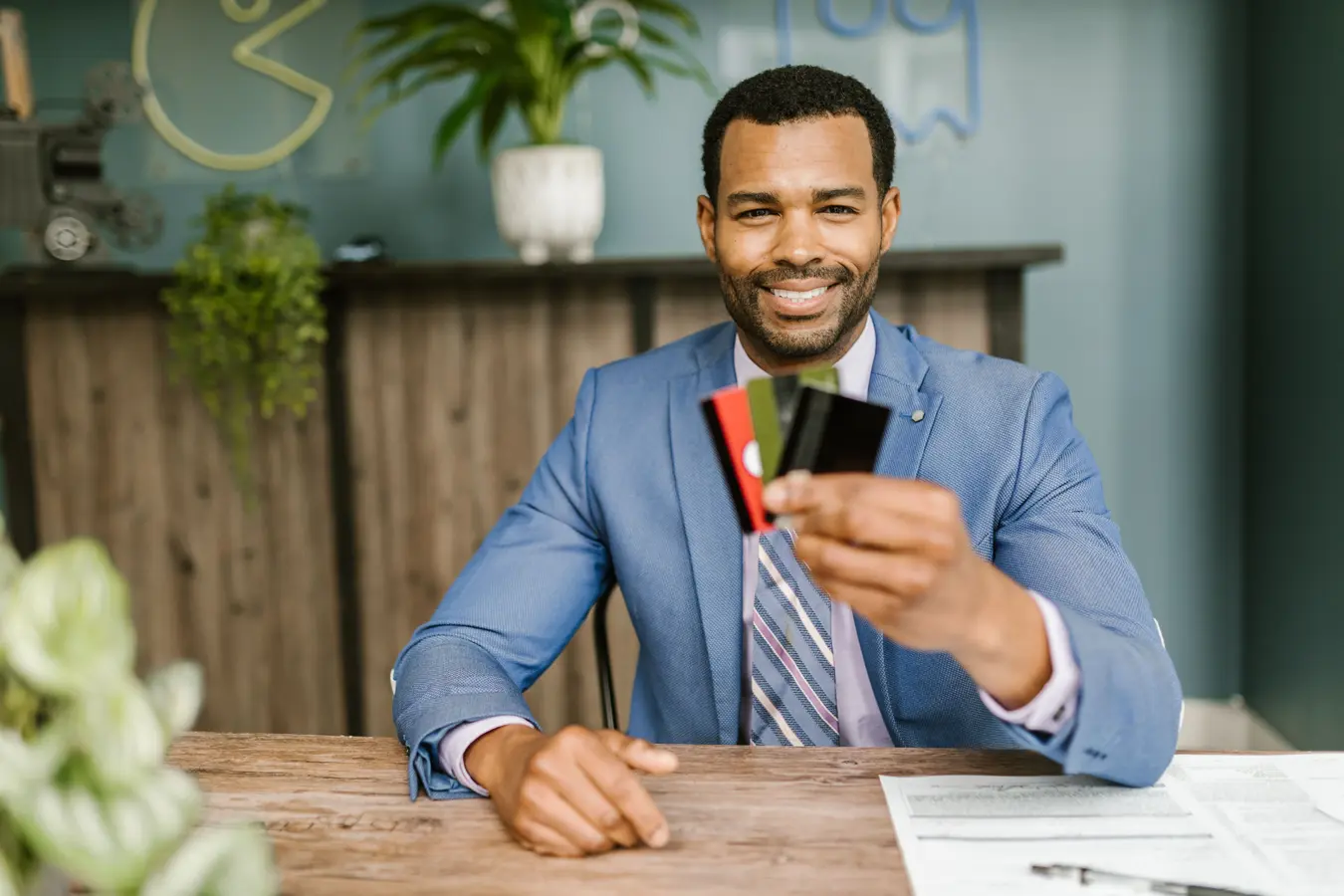 Businessman in a suit holding corporate credit cards at his desk in India