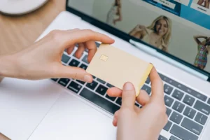 Hands holding a credit card while shopping online on a laptop in India