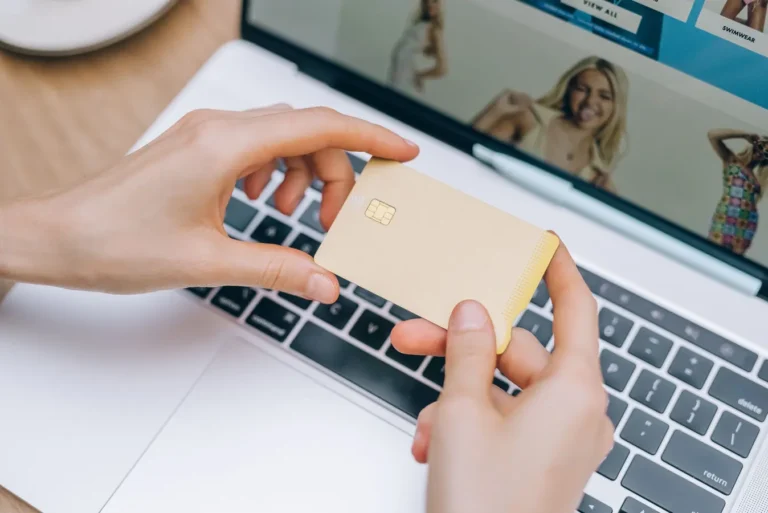 Hands holding a credit card while shopping online on a laptop in India