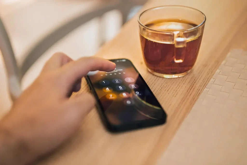 Hand unlocking a smartphone beside a cup of tea, suggesting Bitwarden password manager security