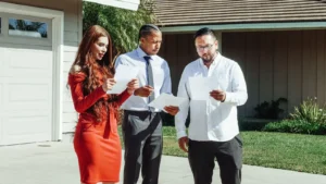 Adults reviewing mortgage loan documents outside a house on a sunny day