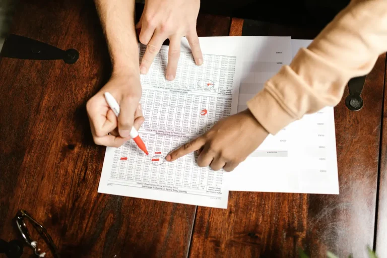 Hands reviewing and marking financial documents with a red pen, illustrating bond intrinsic value formula analysis