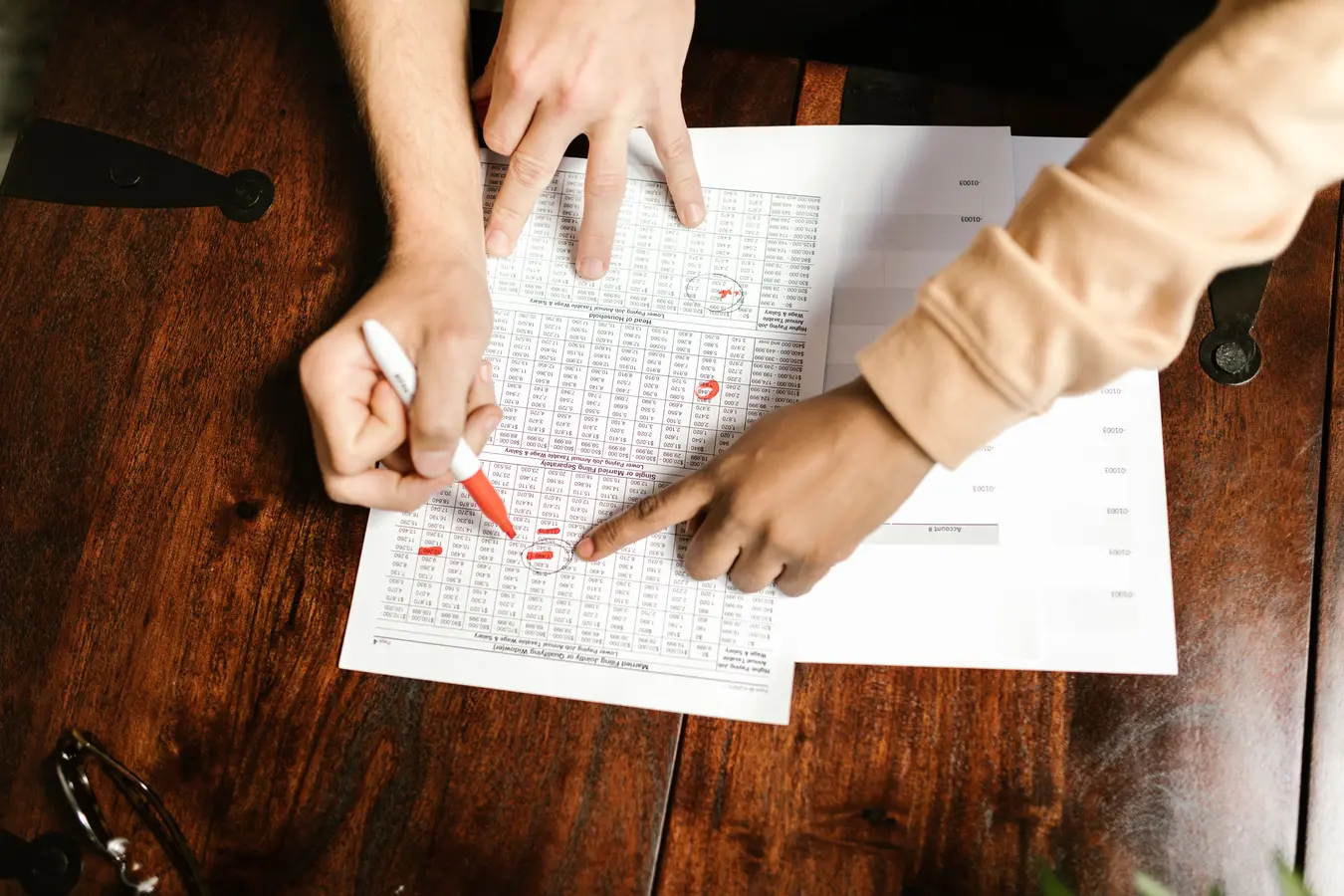 Hands reviewing and marking financial documents with a red pen, illustrating bond intrinsic value formula analysis