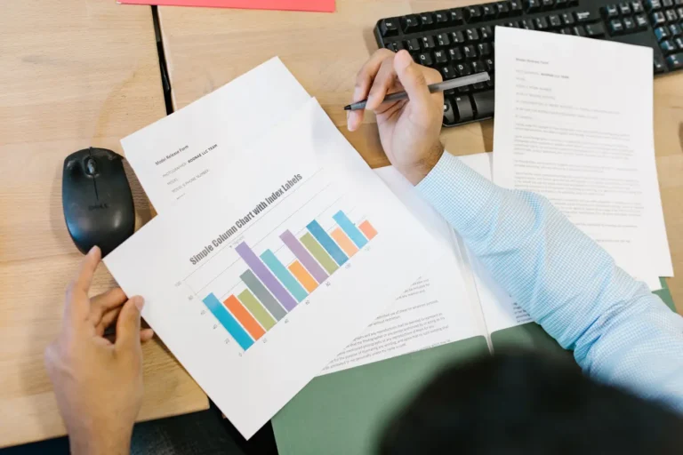 Business analyst reviewing a colorful bar chart and documents to calculate intrinsic value