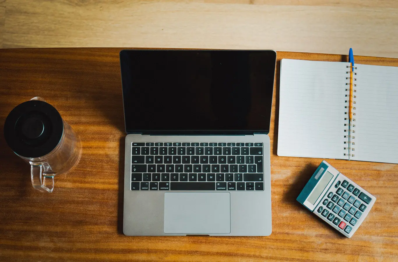 Laptop, calculator, and notebook on a wooden desk for calculate personal loans planning