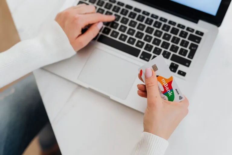 Person using a laptop and holding a credit card for online Capital One credit cards login