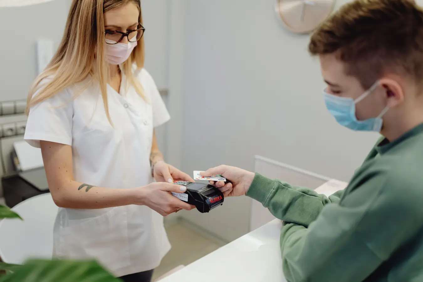 Healthcare professional processing a card payment at a clinic reception desk