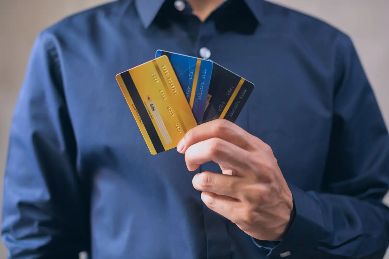 Person holding three credit card rewards cards for finance, security, and online shopping