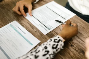 Two people reviewing and filling out a credit card application at a wooden table