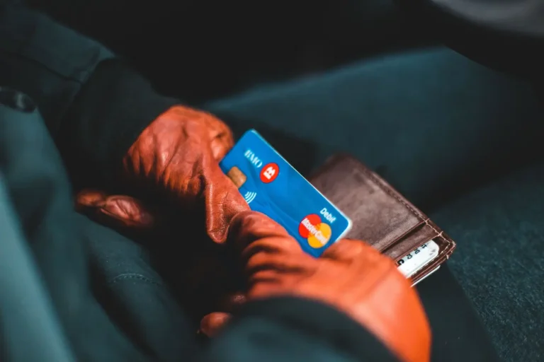 Gloved hands holding a credit card and wallet indoors while comparing credit cards from American Express