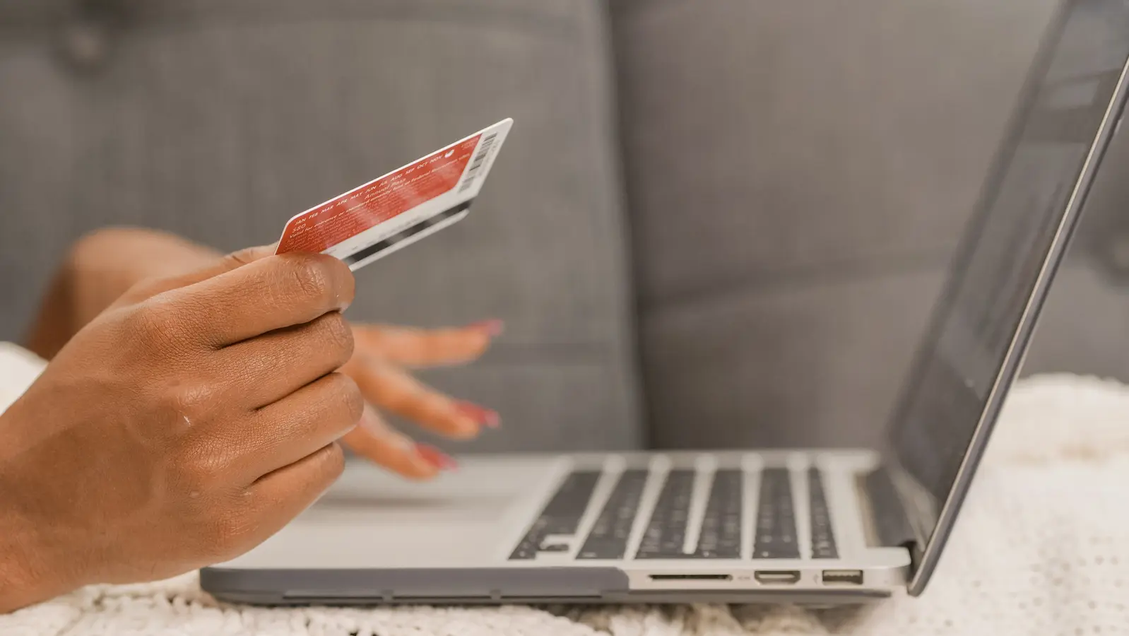 Person using a credit card for online shopping on a laptop, relevant to Amazon purchases