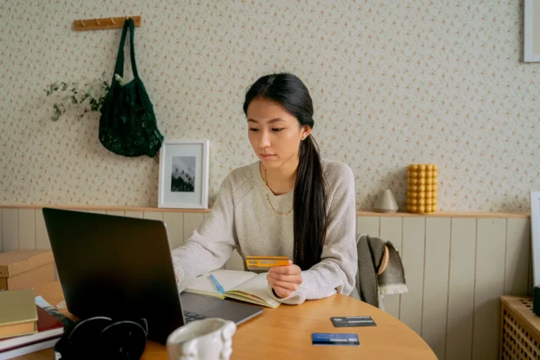 Woman using a laptop and credit card while shopping online at home
