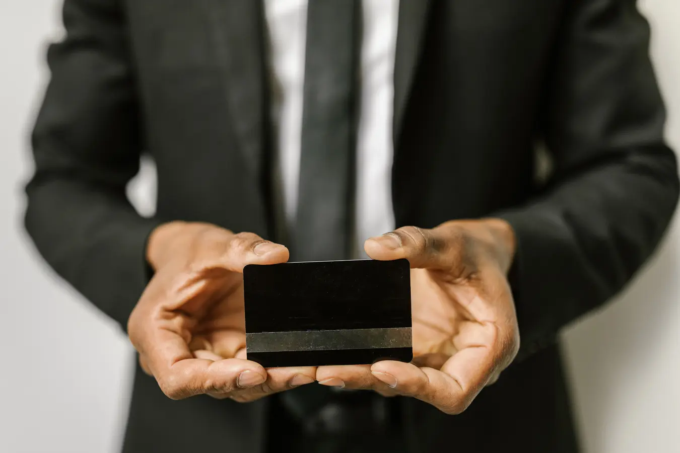Businessman holding a blank credit card in both hands, symbolizing premium travel rewards cards