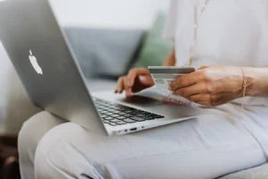 Person holding a credit card while shopping online on a laptop at home
