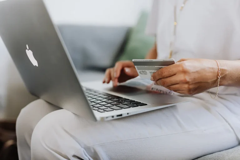 Person holding a credit card while shopping online on a laptop at home