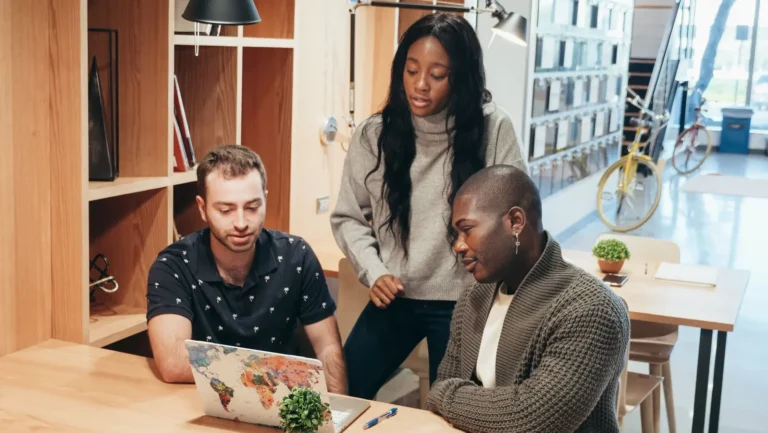 Diverse team discussing ideas around a laptop, planning crm software for a small business