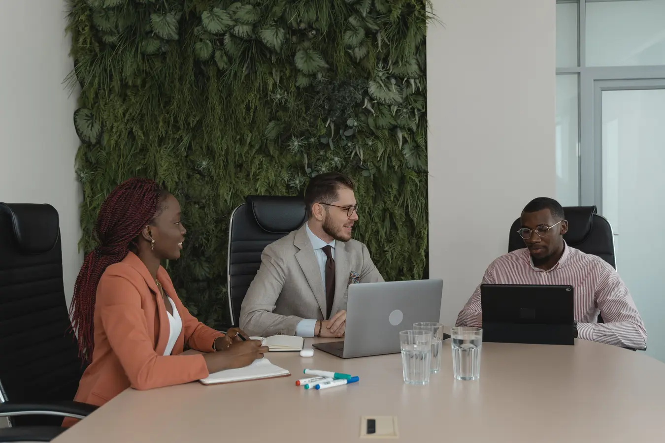 Diverse team collaborating in a modern office with a vertical garden, reflecting ESG investing themes