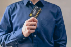 Man in blue shirt holding a credit card, representing best HDFC credit cards