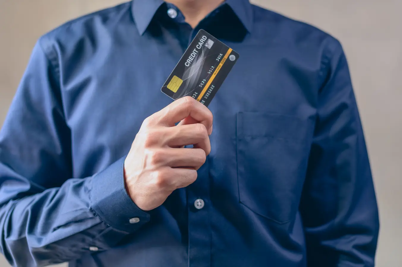 Man in blue shirt holding a credit card, representing best HDFC credit cards