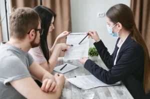 Three adults reviewing insurance documents together at a meeting table indoors