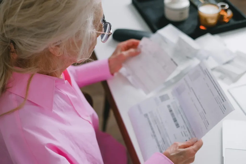 Elderly woman reading important papers at a table, reviewing healthcare savings account documents