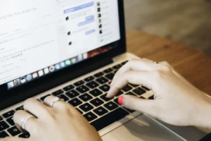 Hands typing on a laptop keyboard with a messaging app open, related to Facebook Business Manager password changes