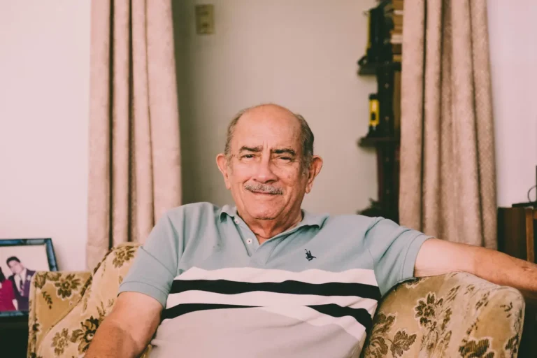 Cheerful elderly man relaxing on a sofa in a warm living room, reflecting intrinsic value of a person