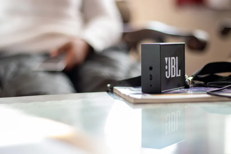 Close-up of a JBL wireless Bluetooth speaker on a reflective table indoors