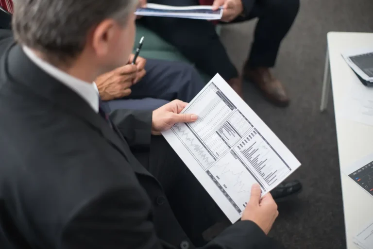 Two businessmen reviewing financial documents and data trends during a meeting on ESG investing jobs