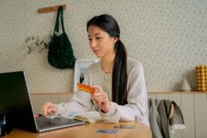 Young woman using a laptop and credit card for online shopping at home in India