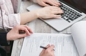 Hands typing on a laptop while reviewing financial documents for a LightStream personal loans article