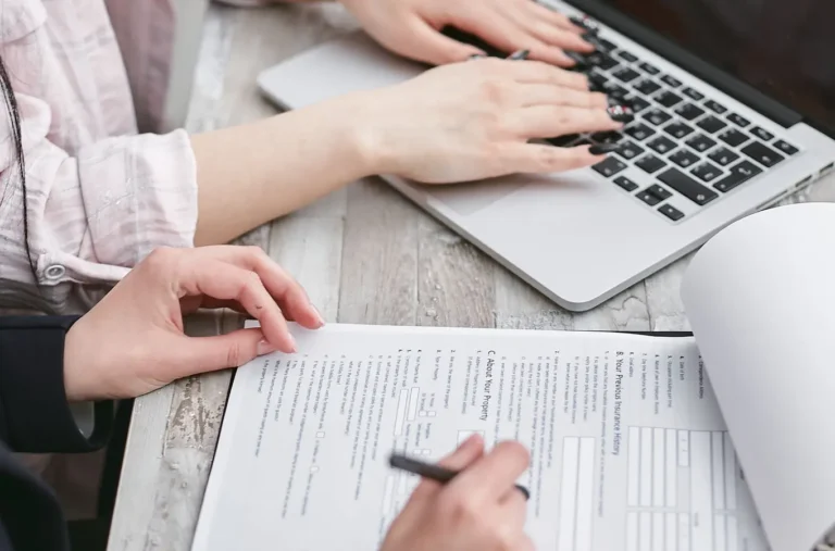 Hands typing on a laptop while reviewing financial documents for a LightStream personal loans article