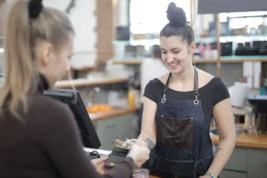 Smiling cashier helping customer with credit card payment at store counter