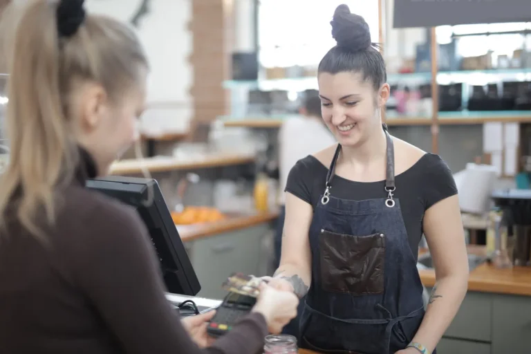 Smiling cashier helping customer with credit card payment at store counter