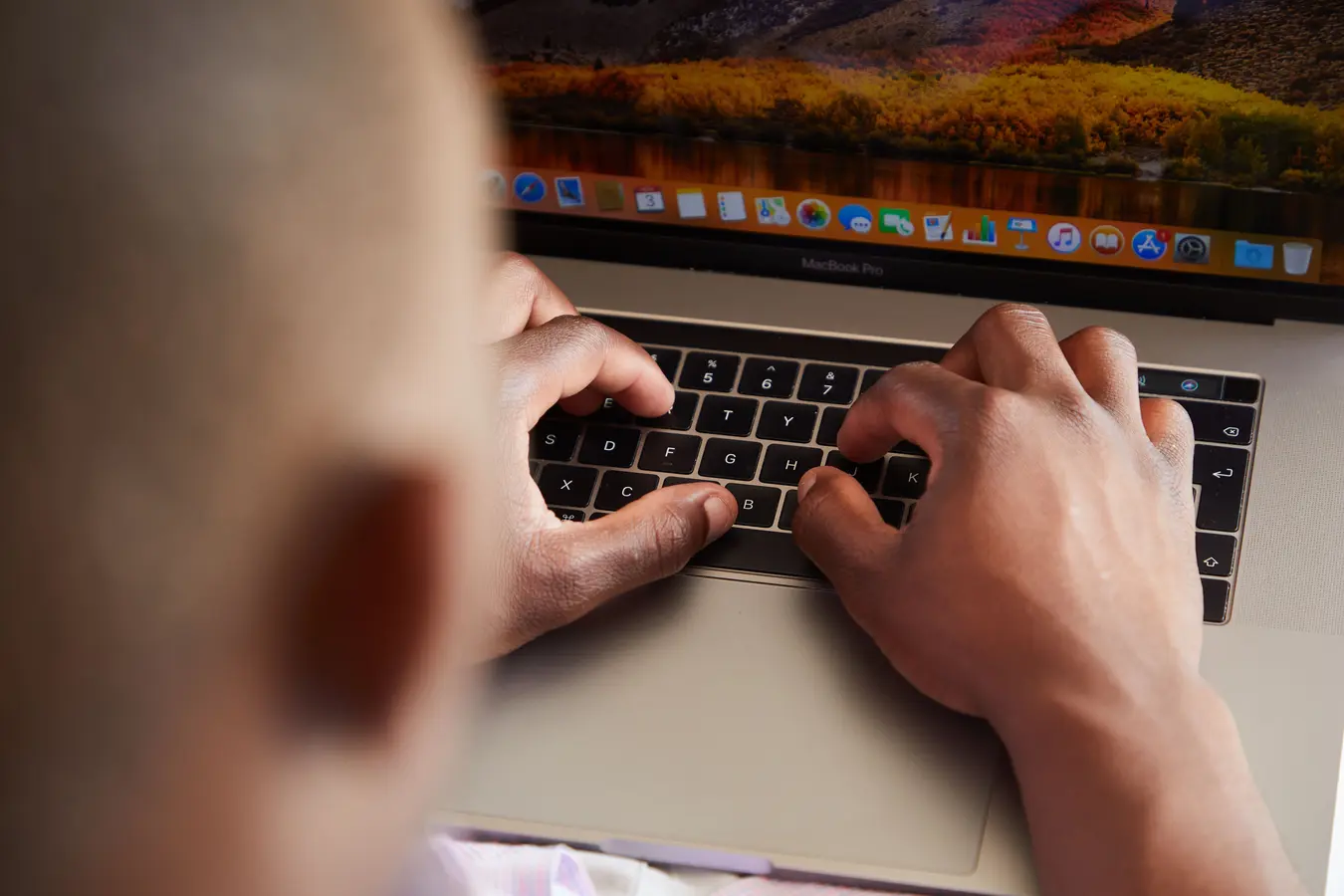 Overhead view of an anonymous man typing on a modern laptop keyboard