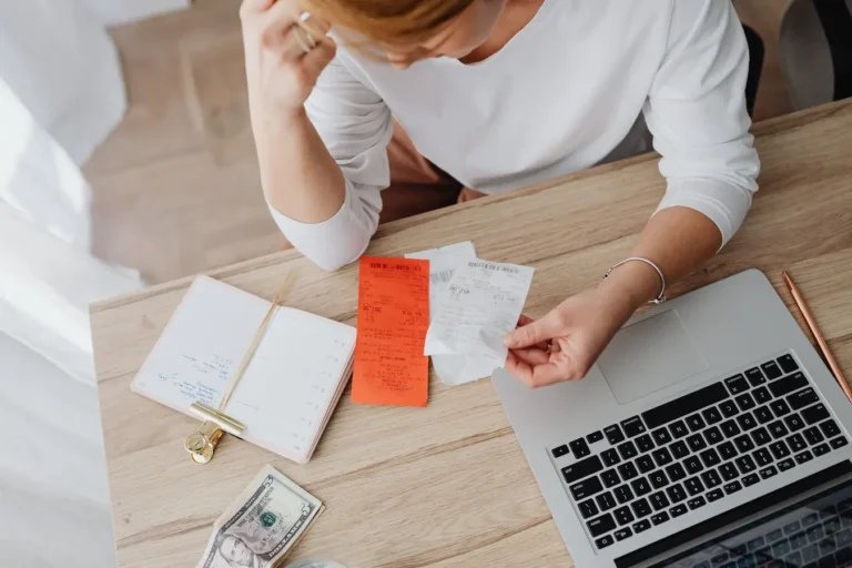 Woman reviewing receipts and budgeting at home with a laptop for medical savings account planning