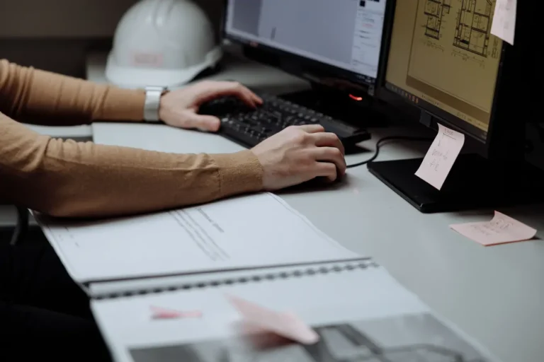 Architect at dual monitors using Microsoft project management software in a modern workspace