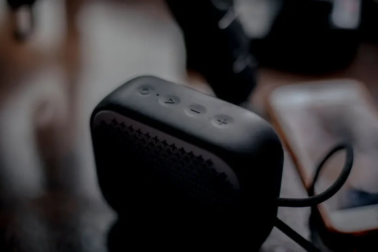 Sleek portable Bluetooth speaker beside a smartphone on a wooden table