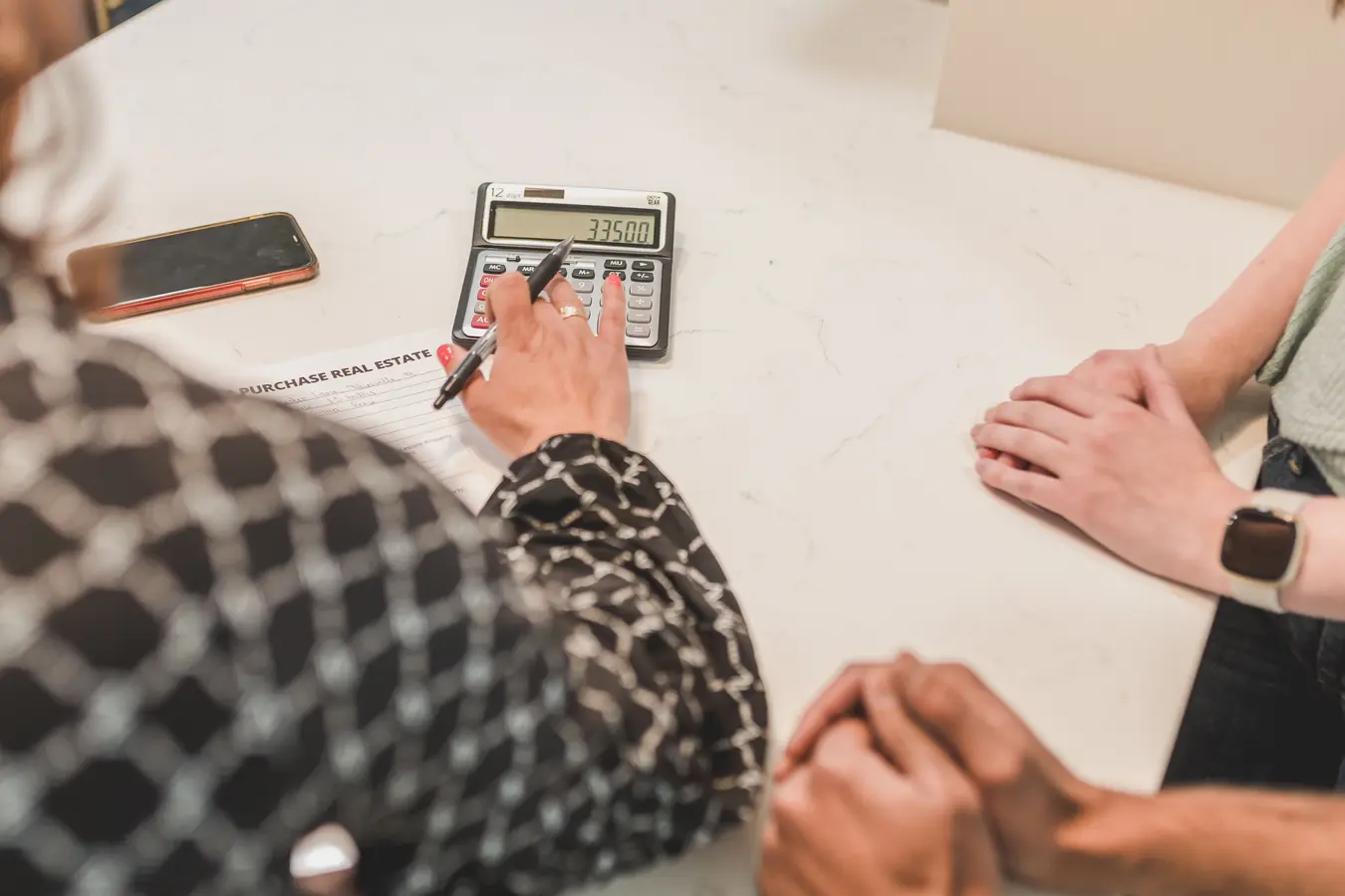 Hands reviewing mortgage paperwork with a calculator during a real estate transaction