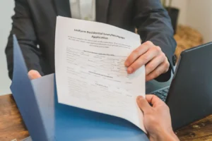Hands exchanging a mortgage application document in a professional indoor setting