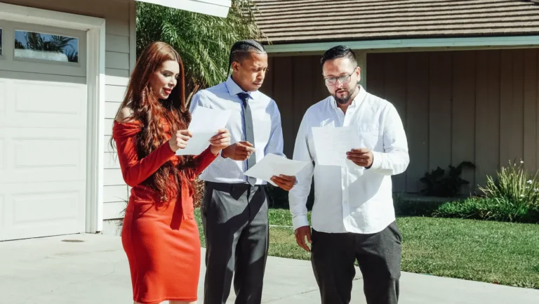 Adults reviewing home purchase documents outside a house while comparing 15-year mortgage rates.