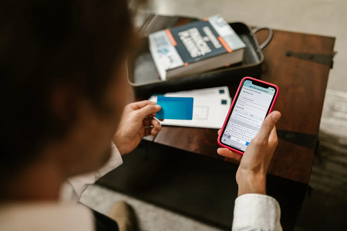 Person making an online payment on a smartphone with a credit card indoors
