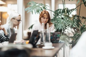 Two women working on laptops in a modern office, reflecting NetSuite CRM software collaboration