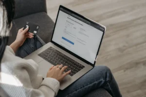 Woman shopping online on a laptop while holding a credit card in hand