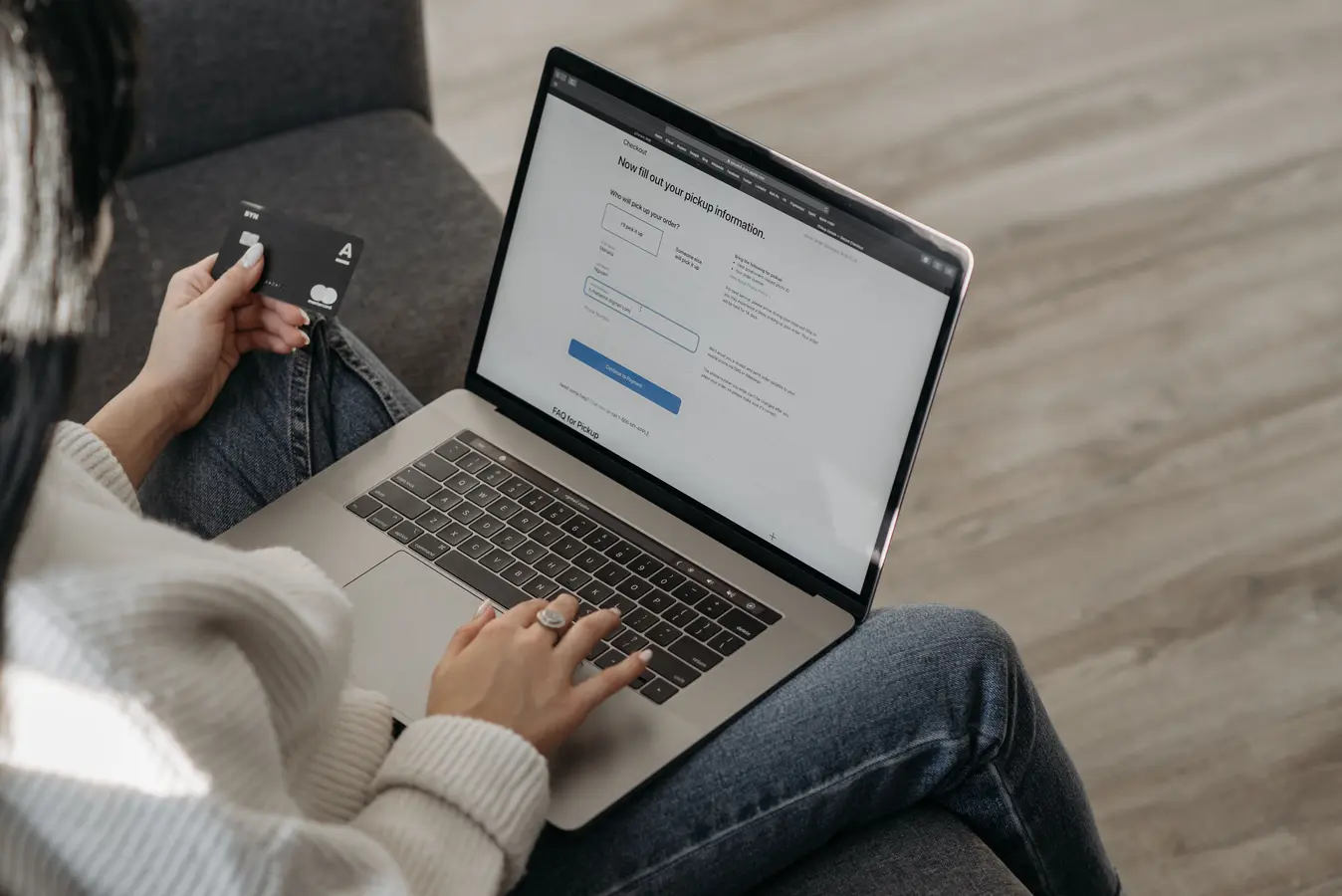 Woman shopping online on a laptop while holding a credit card in hand