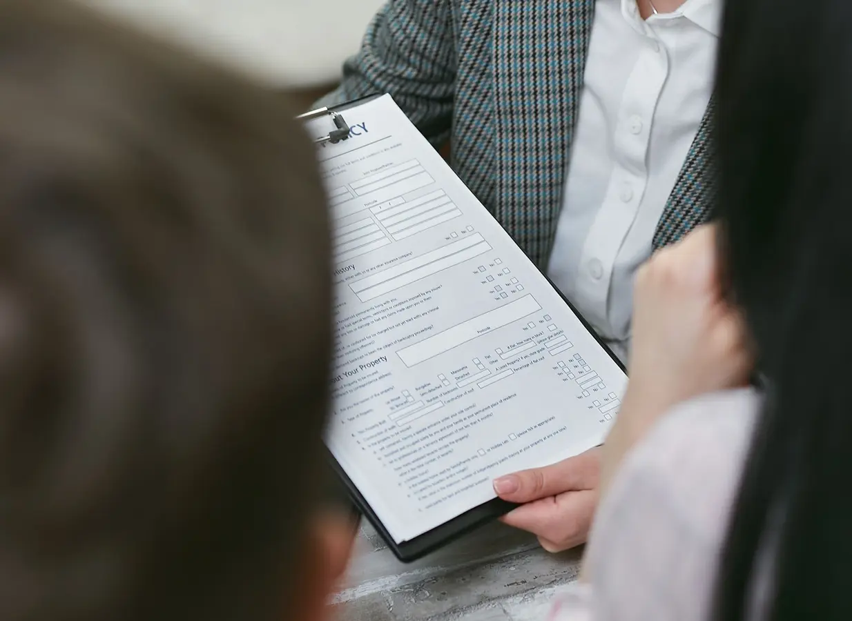 Close-up of professionals reviewing a contract during a business meeting about PITI mortgage terms
